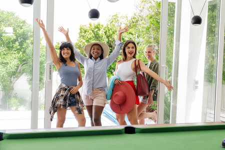 Joyful women entering modern home, smiling and waving, ready for fun day. Friendship, arrival, cheerful, hospitality, excitement, positivityの写真素材