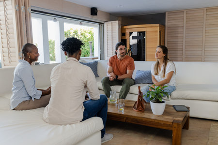 Friends relaxing on sofa, enjoying conversation in cozy living room setting. Socializing, friendship, relaxation, leisure, comfortable, homeの写真素材