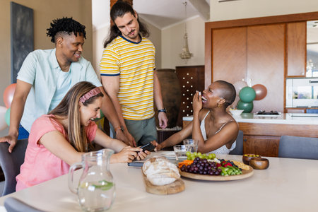 Friends enjoying laughter and conversation around table with snacks and drinks. gathering, celebration, party, socializing, bonding, beveragesの写真素材