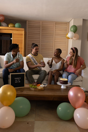 Celebrating new job, diverse friends enjoying drinks and cake at home party. Celebration,...