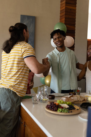 Friends greeting each other warmly at home during casual gathering. Friendship, celebration, meetup, togetherness, party, leisureの写真素材