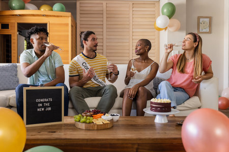 Celebrating new job, diverse friends enjoying drinks and cake at home party. Celebration, happiness, togethernessの写真素材