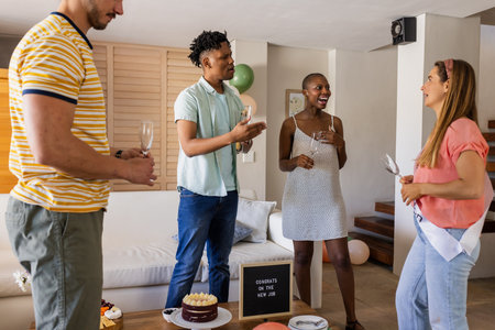 Friends celebrating new job with cake and drinks at home, sharing laughter. Celebration, friendship, party, accomplishment, togetherness, happinessの写真素材