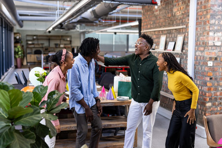 Colleagues in modern office laughing and celebrating successful project together. Teamwork, happiness, collaboration, achievement, corporate, office lifeの写真素材