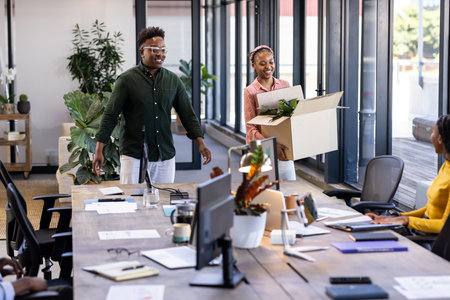 African American colleagues welcoming new team member with box at modern office. Teamwork, collaboration, onboarding, corporate, diversity, coworkingの写真素材
