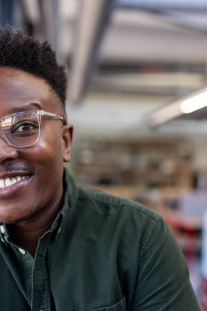 Smiling man in glasses wearing green shirt at modern office workspace. business, professional,...
