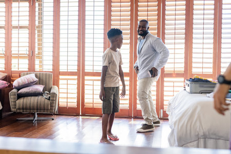 Father and son enjoying playful moment together in bright, cozy bedroom. Family, bonding, fatherhood, fun, childhood, loveの写真素材