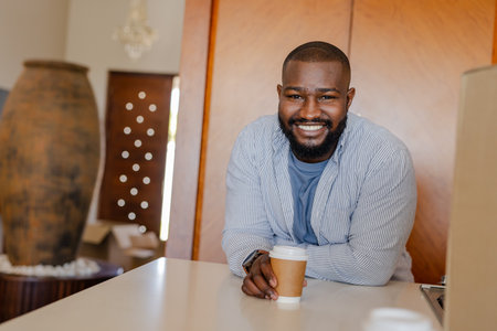Smiling man enjoying coffee at home, leaning on kitchen counter. Lifestyle, relaxation, morning, breakfast, drinkの写真素材