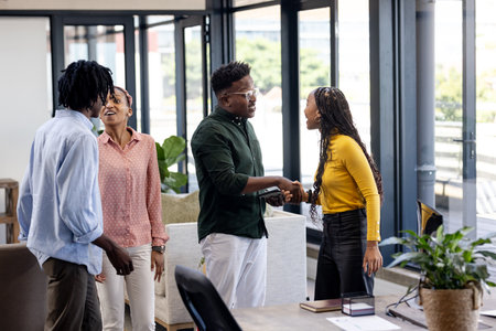 Meeting in modern office, African American professionals greeting and smiling warmly. Business, teamwork, diversity, communication, collaboration, corporateの写真素材