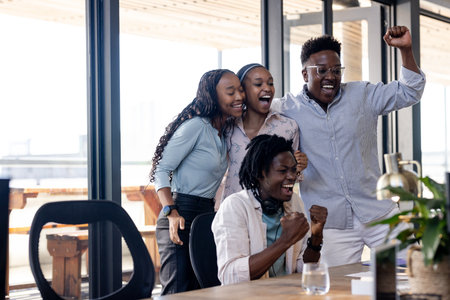 Diverse team celebrating success in modern office, showing excitement and teamwork. collaboration, celebration, business, professionalの写真素材