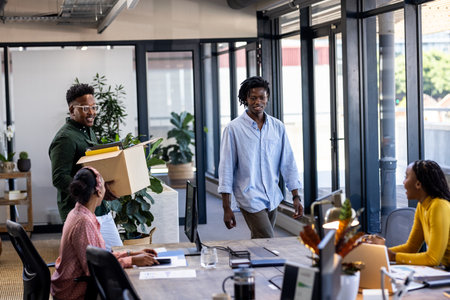 African American colleagues welcoming new team member with box in modern office. Business, teamwork, startup, diversity, corporate, employmentの写真素材