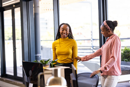 African American women in office smiling and discussing creative business ideas. Teamwork,...