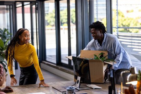 Unpacking box in modern office, African American colleagues smiling and collaborating. Teamwork, collaboration, diversity, workspace, business, projectの写真素材