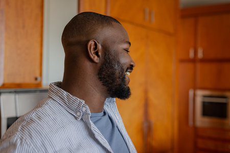 Relaxing in kitchen, man smiling and enjoying peaceful moment at home. Relaxation, lifestyle, leisure, domestic, calm, maleの写真素材