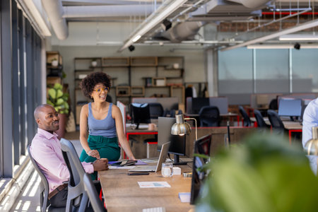 Colleagues collaborating at modern office desk, discussing project with enthusiasm. Teamwork, brainstorming, corporate, innovation, strategy, professionalsの写真素材