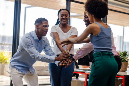 Celebrating success, diverse team collaborating enthusiastically in modern office setting. Teamwork,...
