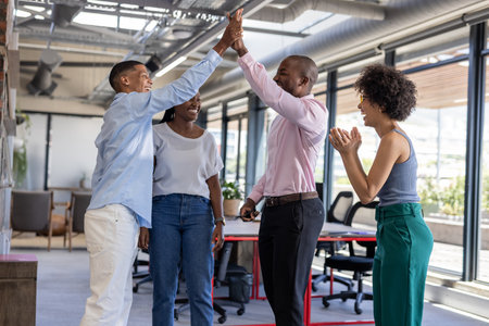Colleagues in office celebrating success with high fives and smiles. Teamwork, collaboration, achievement, victory, excitement, happinessの写真素材