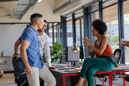 Colleagues discussing project at office desk, sharing ideas and smiling. Collaboration, teamwork, brainstorming, business, meeting, corporateの写真素材