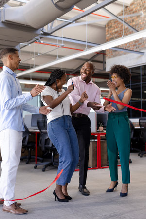 Business team celebrating ribbon cutting ceremony in modern office, feeling excited. celebration, teamwork, success, collaboration, entrepreneurship, professionalの写真素材