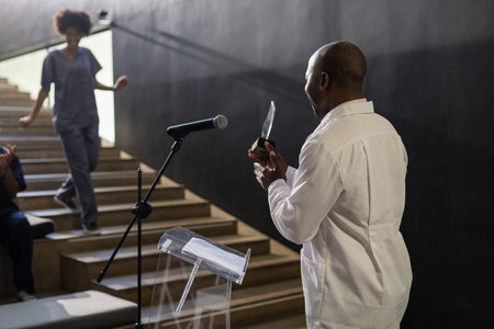 Presenting award on stage, medical professional applauded by audience in auditorium. Recognition, achievement, celebration, applause, ceremony, healthcareの写真素材