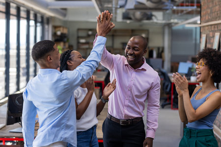 Colleagues celebrating success with high fives and smiles in modern office. Teamwork, celebration, corporate, achievement, collaboration, happinessの写真素材