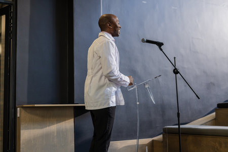 Speaking confidently at podium, businessman presenting at professional event. Public speaking, presentation, conference, leadership, communication, corporateの写真素材