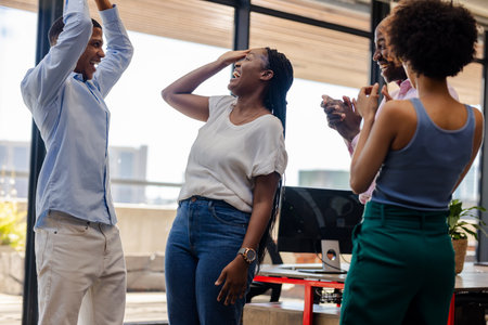 Colleagues celebrating success in office, smiling and clapping with excitement. Teamwork, collaboration, achievement, celebration, enthusiasm, happinessの写真素材
