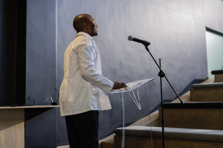 Presenting confidently, businessman speaking at podium during professional conference. Public speaking, leadership, presentation, corporate, speechの写真素材