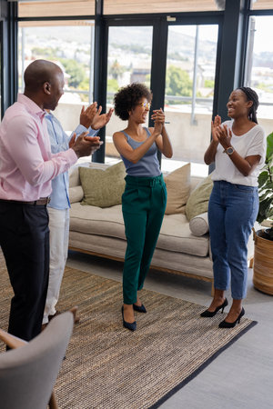 Colleagues applauding and celebrating success in modern office with large windows.の写真素材