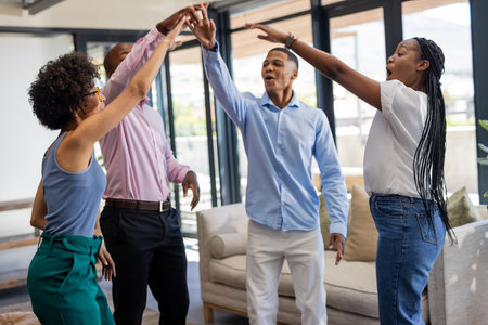 Colleagues celebrating success with high fives in modern office lounge area. Teamwork, collaboration, achievement, corporate, celebration, workplaceの写真素材