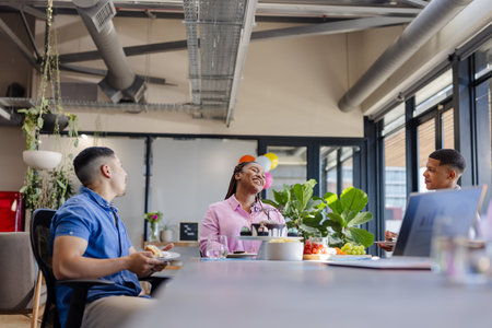 Colleagues enjoying lunch and conversation in modern office break room. Coworkers, teamwork,...
