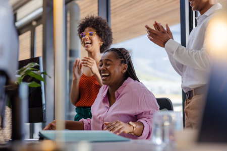 African American woman laughing with colleagues in office during successful meeting. Teamwork, collaboration, professional, business, corporate, communicationの写真素材