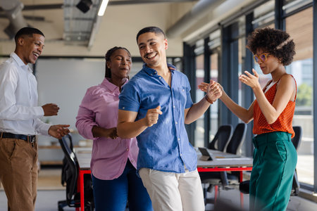 Dancing and laughing, colleagues enjoying lively break together in office. Teamwork, collaboration, workplace, cheerful, joyful, bondingの写真素材