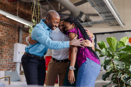 Colleagues in office hugging and celebrating success with joyful expressions. Teamwork, collaboration, celebration, happiness, workplace, achievementの写真素材