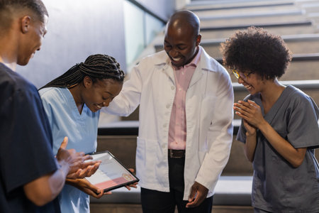 Celebrating colleague's award, medical team showing appreciation in hospital hallway. Healthcare, teamwork, recognition, achievement, celebration, coworkersの写真素材