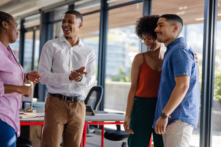 Colleagues laughing and chatting in modern office, enjoying team bonding moment. Coworkers, teamwork, collaboration, business, professional, communicationの写真素材