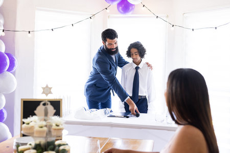 Father and son in suits speaking at family celebration, sharing joyful moment. bonding, happiness, togetherness, formal, enjoyment, parenthoodの写真素材