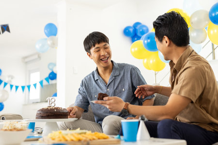 Celebrating birthday, two friends enjoying cake and laughter at home party. Celebration, friendship, happiness, dessert, occasion, gatheringの写真素材