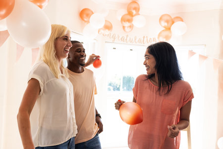 Happy senior diverse female friends eating cake and drinking coffee at birthday partyの写真素材