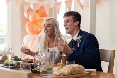 Bride and groom joyfully toasting at wedding reception with festive decorations. Celebration, marriage, happiness, romance, newlyweds, eventの写真素材
