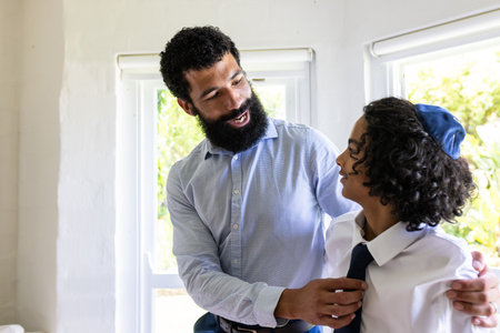 Father helping son with tie, both smiling, preparing for bar mitzvah. Family, bonding, preparation, tradition, fatherhood, ceremonyの写真素材