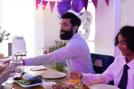 Family enjoying festive meal together, sharing laughter and joy at celebration. Family gathering,...