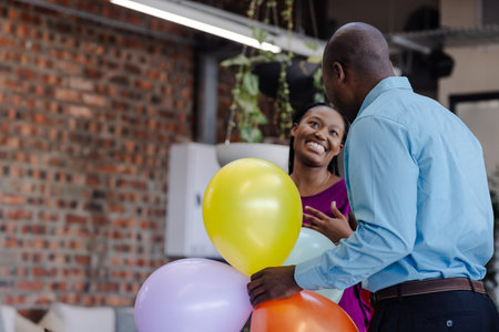 Smiling colleagues holding colorful balloons, celebrating in modern office space. Teamwork,...