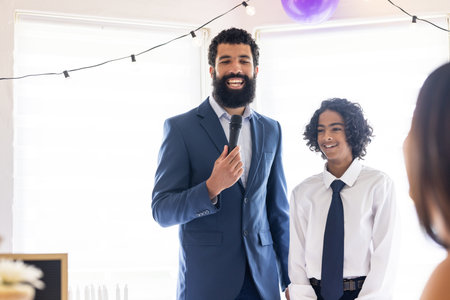 Man in suit speaking into microphone with smiling boy at celebration event. speech, formal, interaction, joyful, communication, gatheringの写真素材
