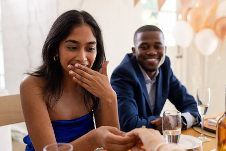 Guests celebrating at wedding reception, woman surprised and smiling at table. Celebration, happiness, joy, bride, groom, toastの写真素材