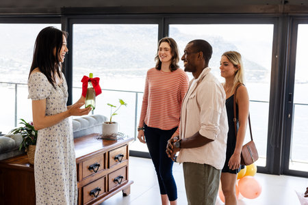 Friends celebrating with gift exchange in living room, smiling and enjoying moment. Celebration, friendship, gifting, happiness, indoors, togethernessの写真素材