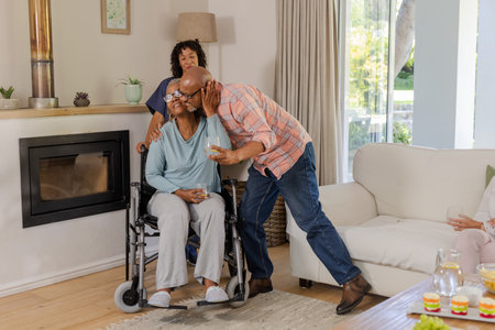 Elderly man kissing woman in wheelchair while friend smiles at home. Friendship, caregiving, senior,...