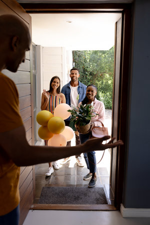 Welcoming friends at home with balloons and gifts, celebrating together joyfully. Celebration, party, friendship, togetherness, happiness, gatheringの写真素材