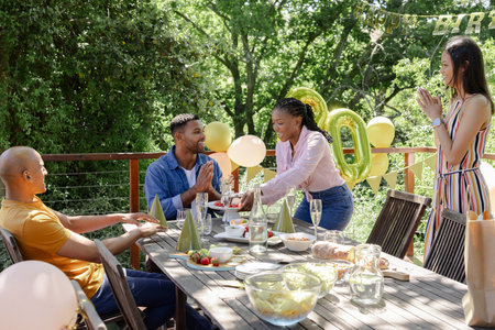 Celebrating birthday outdoors, friends with balloons and food in festive gathering. Celebration, party, festivity, happiness, joyの写真素材