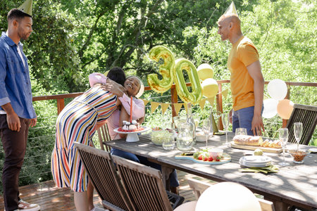 Friends celebrating 30th birthday outdoors, hugging and enjoying festive decorations. Celebration,...